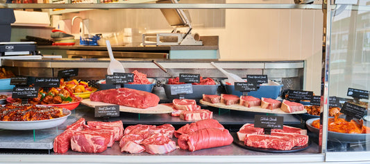 Butcher’s display counter using tiered platforms to elevate cuts of beef and prepared dishes, creating a structured and premium presentation.