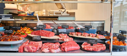 Butcher’s display counter using tiered platforms to elevate cuts of beef and prepared dishes, creating a structured and premium presentation.