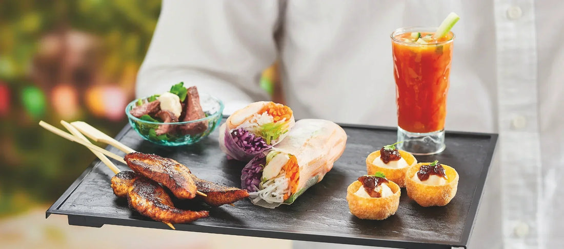 Canapé skewers served in small glass cups with dipping sauce on a wooden board for summer event catering