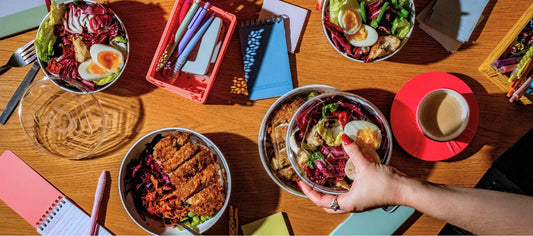 Office catering food-to-go salads served in reusable bowls on a shared workspace table, designed for modern workplace lunches.