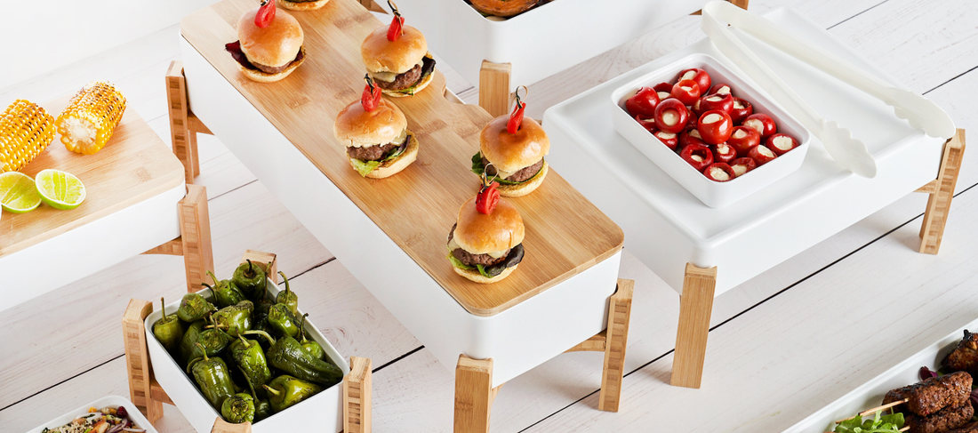 White Kata melamine crocks displayed on bamboo buffet stands with assorted catering dishes