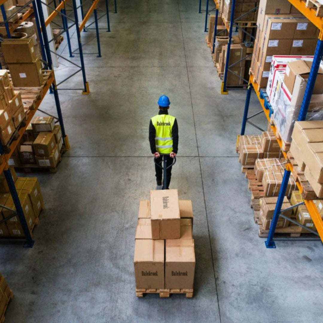 Warehouse worker moving pallet of Dalebrook boxes through storage aisles, representing logistics and distribution