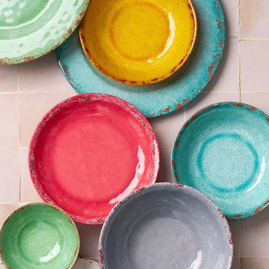 Colourful melamine plates and bowls with textured finish, arranged in a vibrant tabletop display