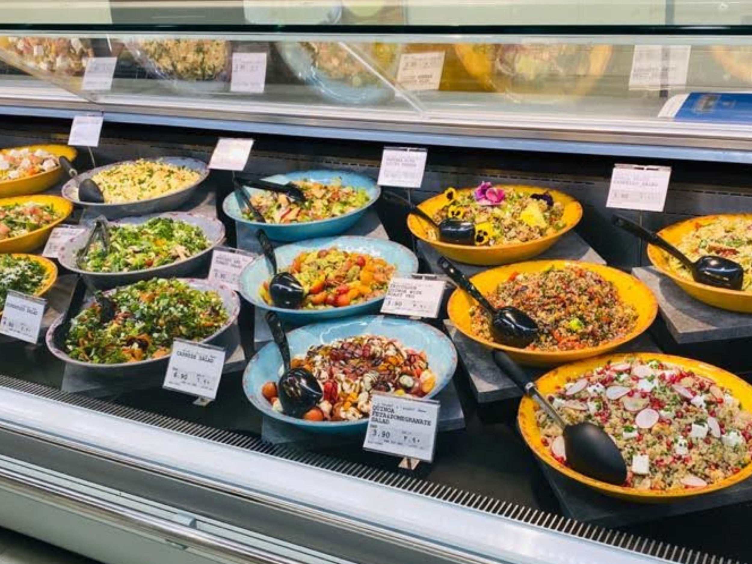 Vibrant supermarket deli counter display with large ceramic bowls of fresh Middle Eastern salads, designed for high-impact presentation to attract customers and boost sales in GCC retail environments.