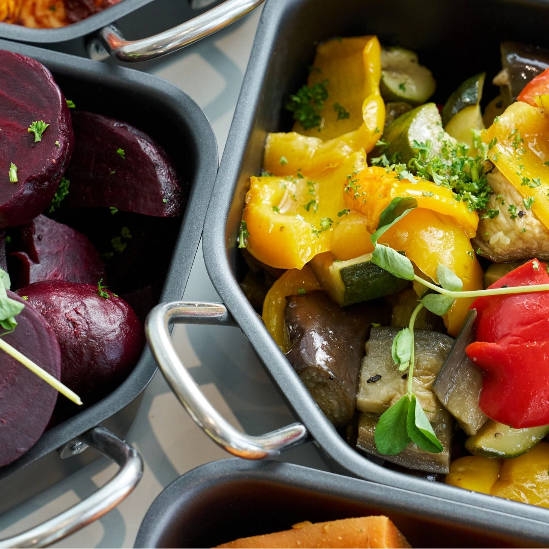 Stainless steel hot counter dishes filled with vegetables and prepared food, designed for food service display